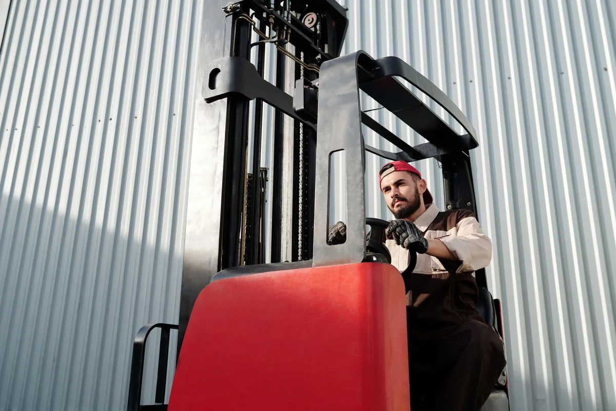An operator driving a forklift beside an industrial building.