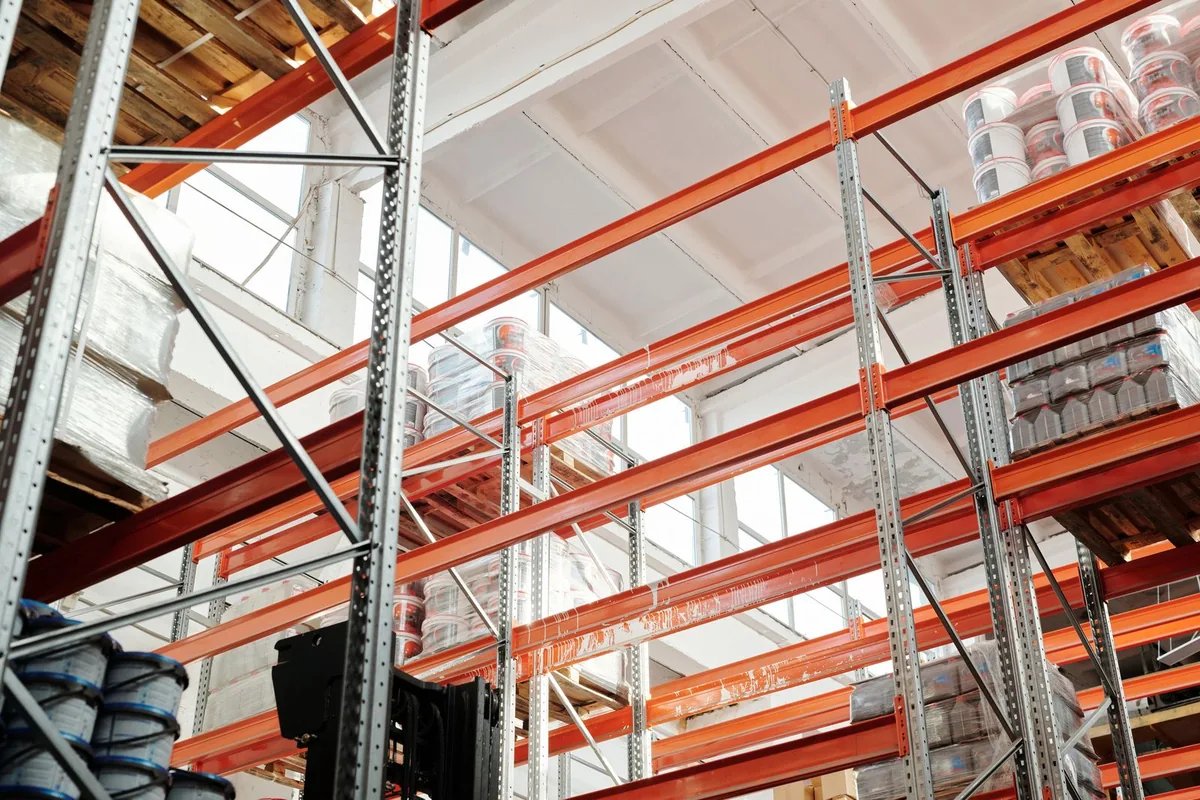 Orange storage racks holding wrapped pallets and goods in a bright warehouse.